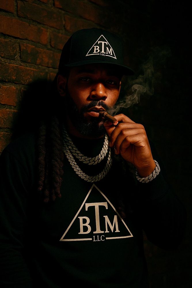 Man in black BTM hat and shirt smoking a cigar with chains around his neck.