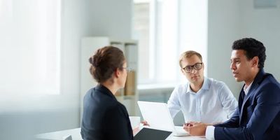 Three professionals engaged in a serious business meeting in a bright office.