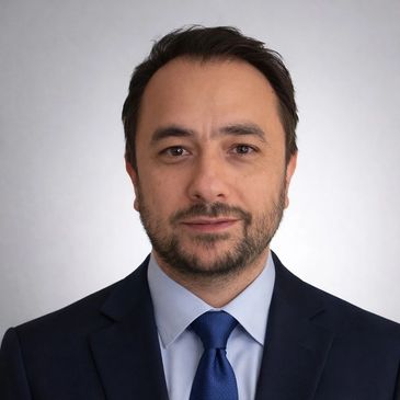 Professional headshot of a man in a suit and tie against a neutral background.