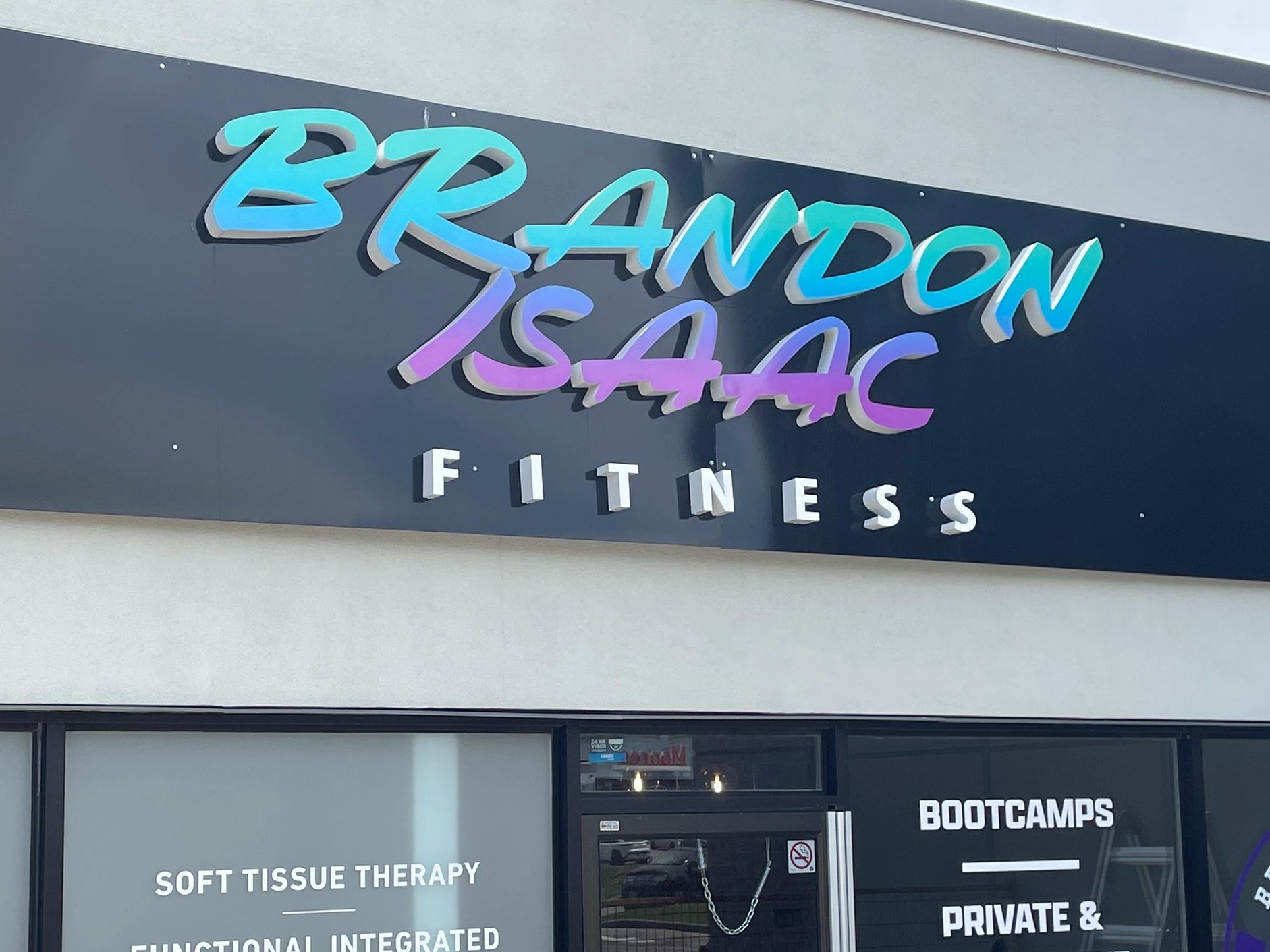 Sign for Brandon Isaac Fitness with colorful letters and fitness services listed.