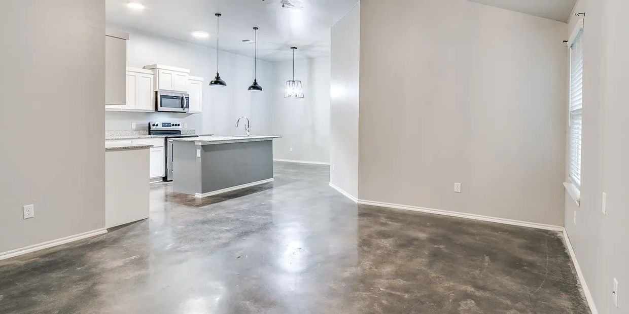 Modern kitchen with polished concrete floors and white cabinetry.