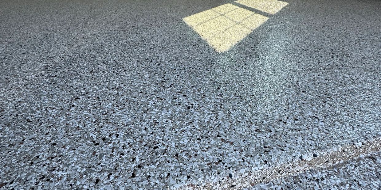 Speckled epoxy garage floor with sunlight casting a window shadow.