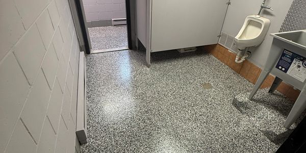 Clean public restroom with terrazzo flooring and a urinal.