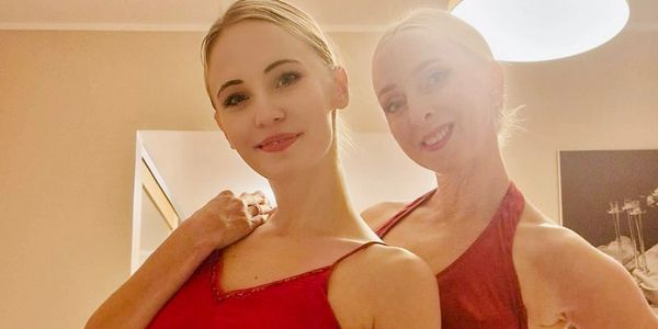 Two women in red dresses smiling indoors.