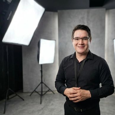 Man in black shirt smiling in a photography studio.