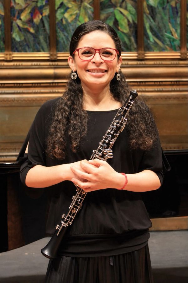 Woman smiling and holding an oboe.