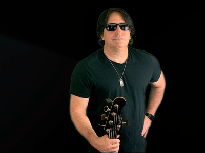 Man in sunglasses holding a guitar on black background.