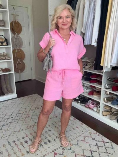 Woman in a pink outfit posing confidently in a stylish closet.