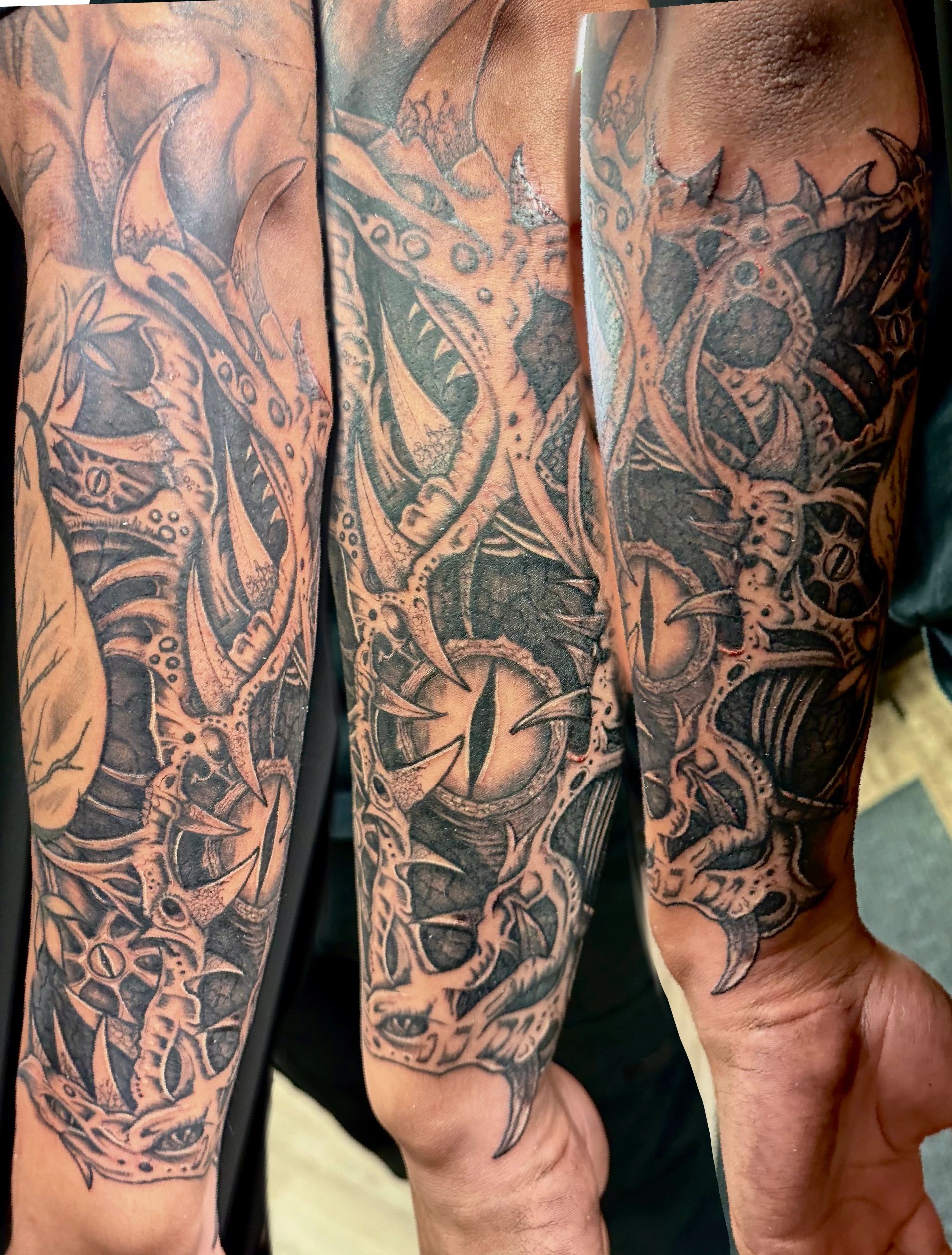 Intricate black and grey biomechanical dragon tattoo sleeve.