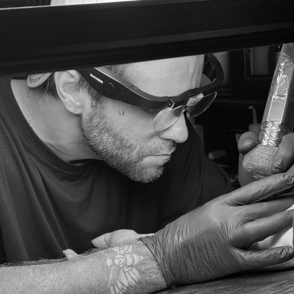Tattoo artist focused on work in black and white.
