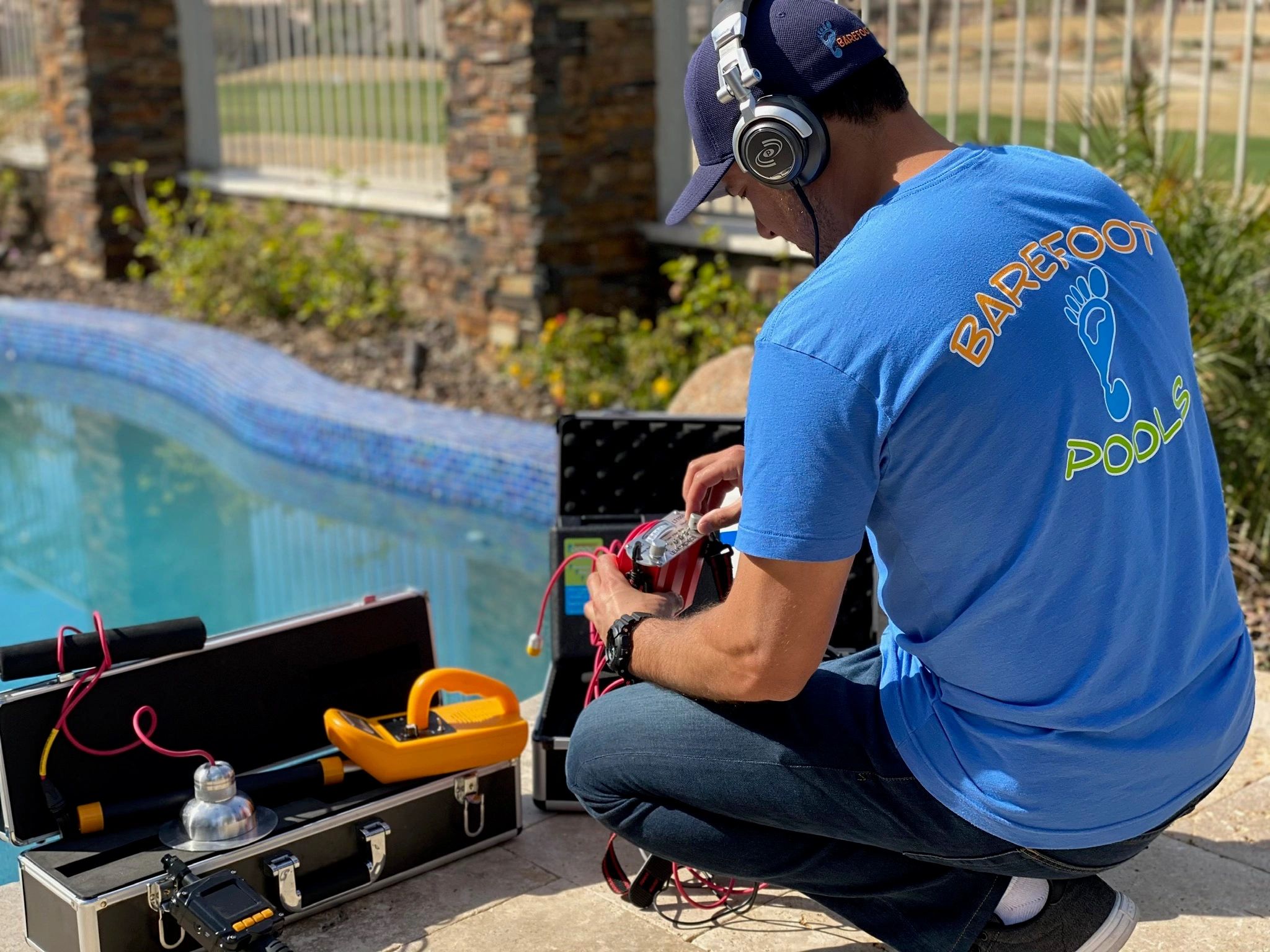 Barefoot Pools technician using professional electronic leak-detection equipment beside an Arizona s
