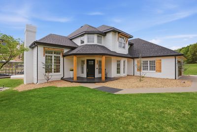 Modern white house with wooden accents and lush green lawn.