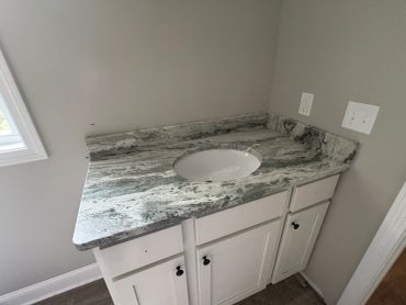 Granite countertop with white cabinets under a bathroom sink.