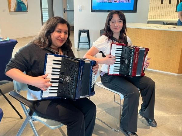 Two women sitting and playing accordions indoors.