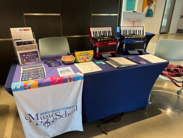 Music school display table with accordions and educational materials.