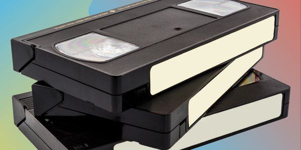 Stack of three black VHS tapes with blank labels on a colorful gradient background.