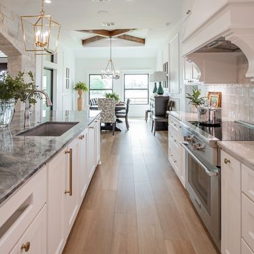 Bright modern kitchen with white cabinetry and wood flooring.