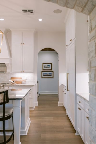 Bright kitchen with white cabinetry and wooden floors.