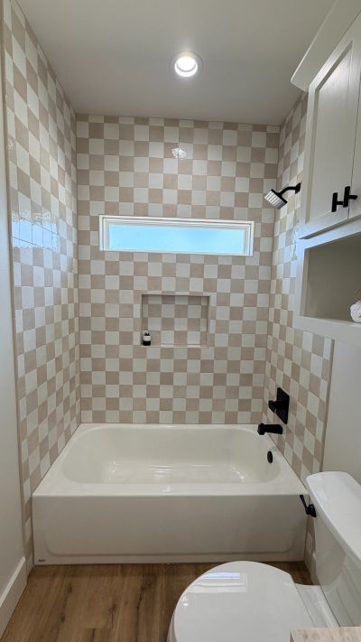Bathroom with checkered tile design and white bathtub.
