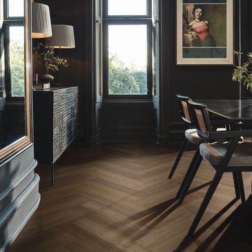 Dark, elegant dining room with wooden floor and large window.