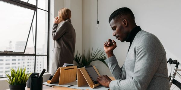 A man looking in the tablet and a woman speaking on the mobile