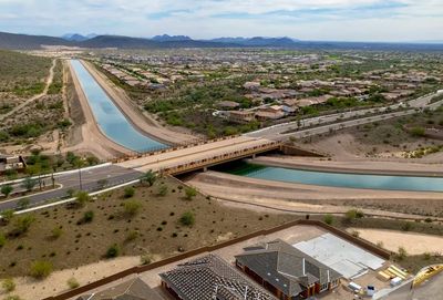 Aerial view of a canal passing under a bridge in a suburban area.