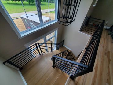 Modern staircase with black railing and wooden steps.