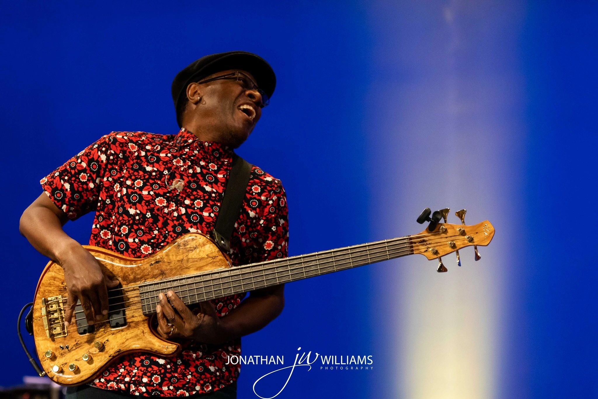 Musician joyfully playing bass guitar on stage.
