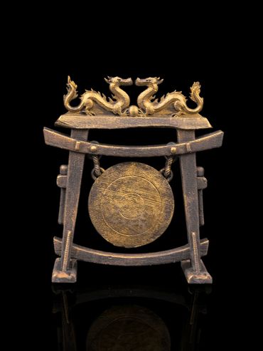 Ornate bronze gong with dragon motifs on a black background.