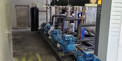 Industrial blue pumps and pipes arranged in a mechanical room.