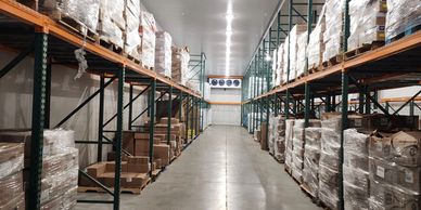 Well-organized warehouse aisle with stacked pallets wrapped in plastic.