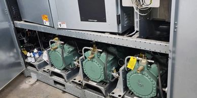 Three green compressors installed in an industrial cooling system.