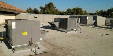 Multiple HVAC units installed on a flat rooftop under clear skies.
