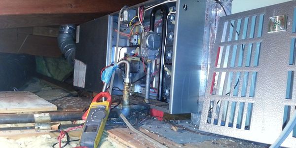 Open furnace with a multimeter testing electrical components.