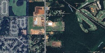 Aerial view of a mixed urban and forest area with sports fields.