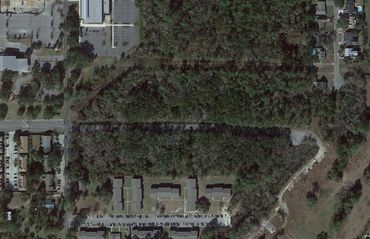 Aerial view of a wooded area surrounded by buildings and roads.
