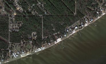 Aerial view of a coastal residential area with houses along the shoreline.