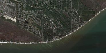 Aerial view of a coastal residential area with houses along the shoreline.