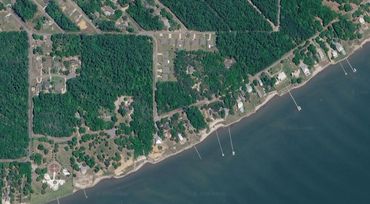 Aerial view of a coastline with greenery and docks.