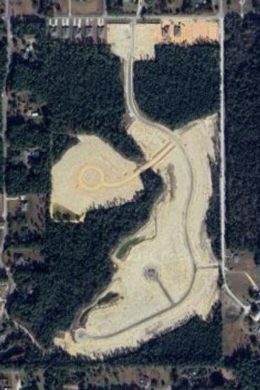 Aerial view of a sandy construction or excavation site surrounded by forest.