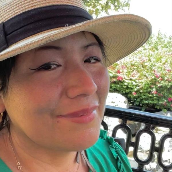 Woman wearing a sunhat smiling outdoors.