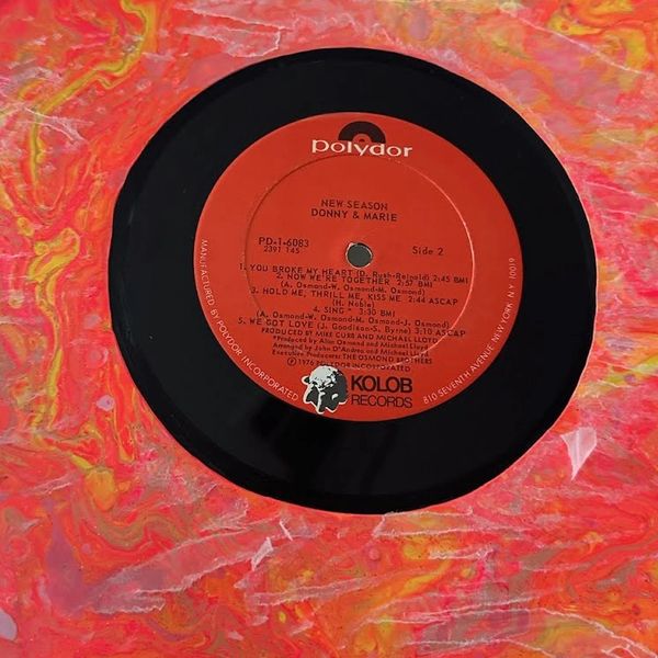 Close up image of a painted vinyl record with the vintage label preserved in the center
