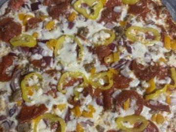 Close-up of a pizza topped with cheese, pepperoni, and yellow bell peppers.