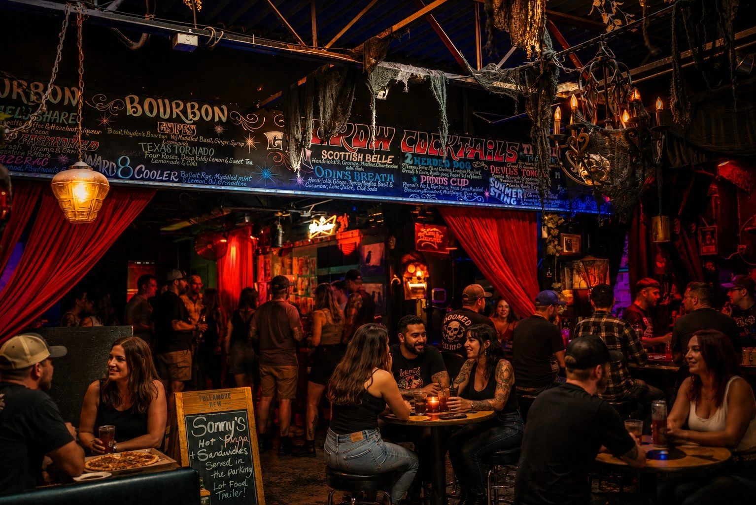The main room at Crow Bar Austin on a busy night, chalkboard cocktail list overhead and red curtains