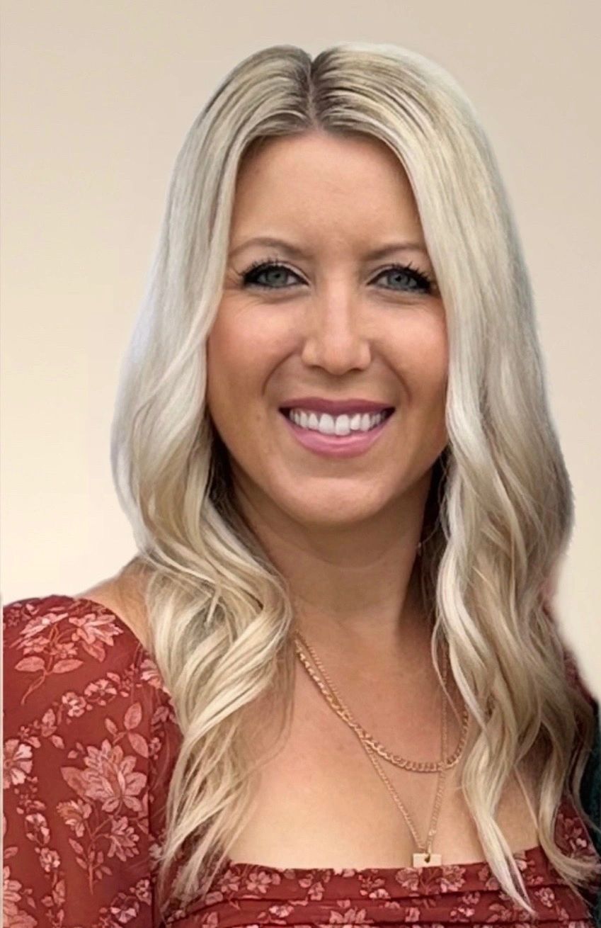 Smiling woman with long blonde hair in a red floral dress.