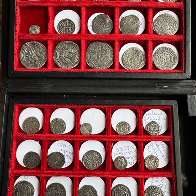 A collection of old silver coins in a red velvet display case.