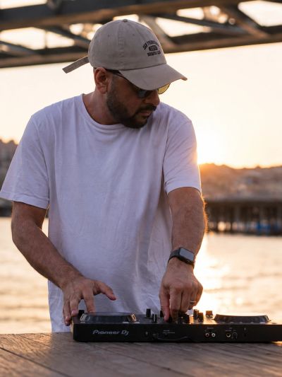 Man DJing outdoors at sunset.