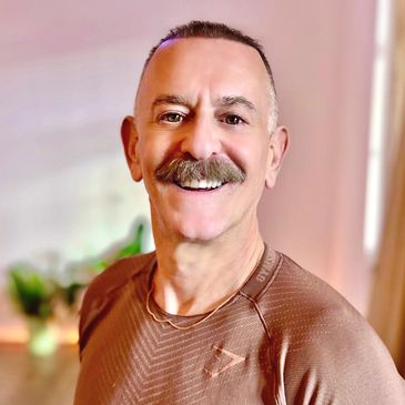 Smiling man with mustache in a brown shirt.