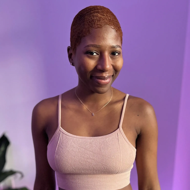 Smiling woman in a light pink top against a purple background.