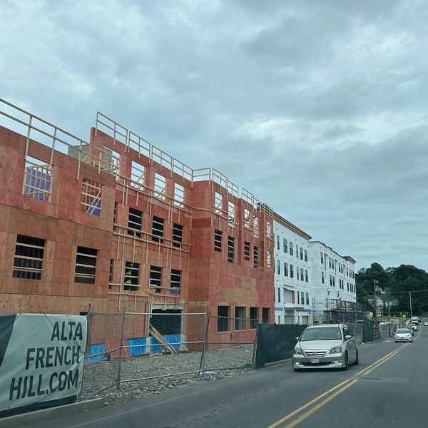New building under construction along a street with cars.
